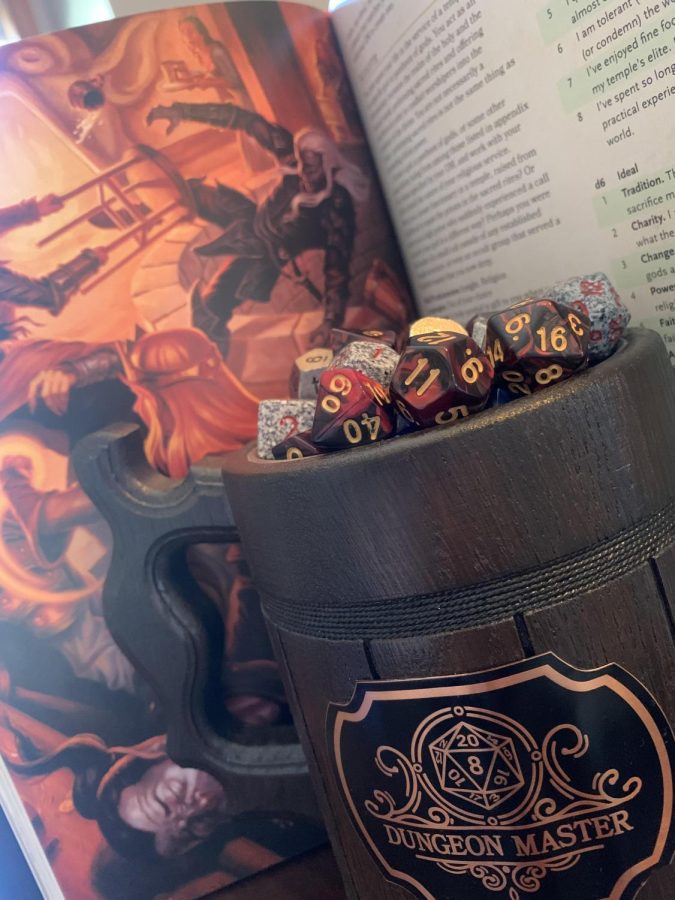 A mug full of dice in front of a Dungeons and Dragons Players handbook. Karissa Lyons photo.